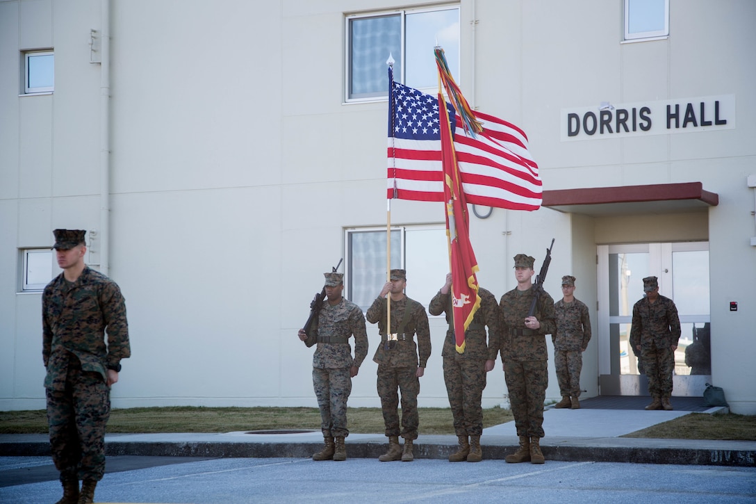 Marines from 3rd Marine Division, Camp Courtney, Okinawa, Japan, stand at attention as a sign of respect during the revealing of the staff non-commissioned officer barracks’ name on Camp Courtney, Okinawa, Japan, Dec. 22, 2017. Dorris Hall is named after the Navy Cross recipient, Staff Sgt. Claude H. Dorris, a squad leader with the Combined Action Program during the Vietnam War, who went above and beyond the call of duty.