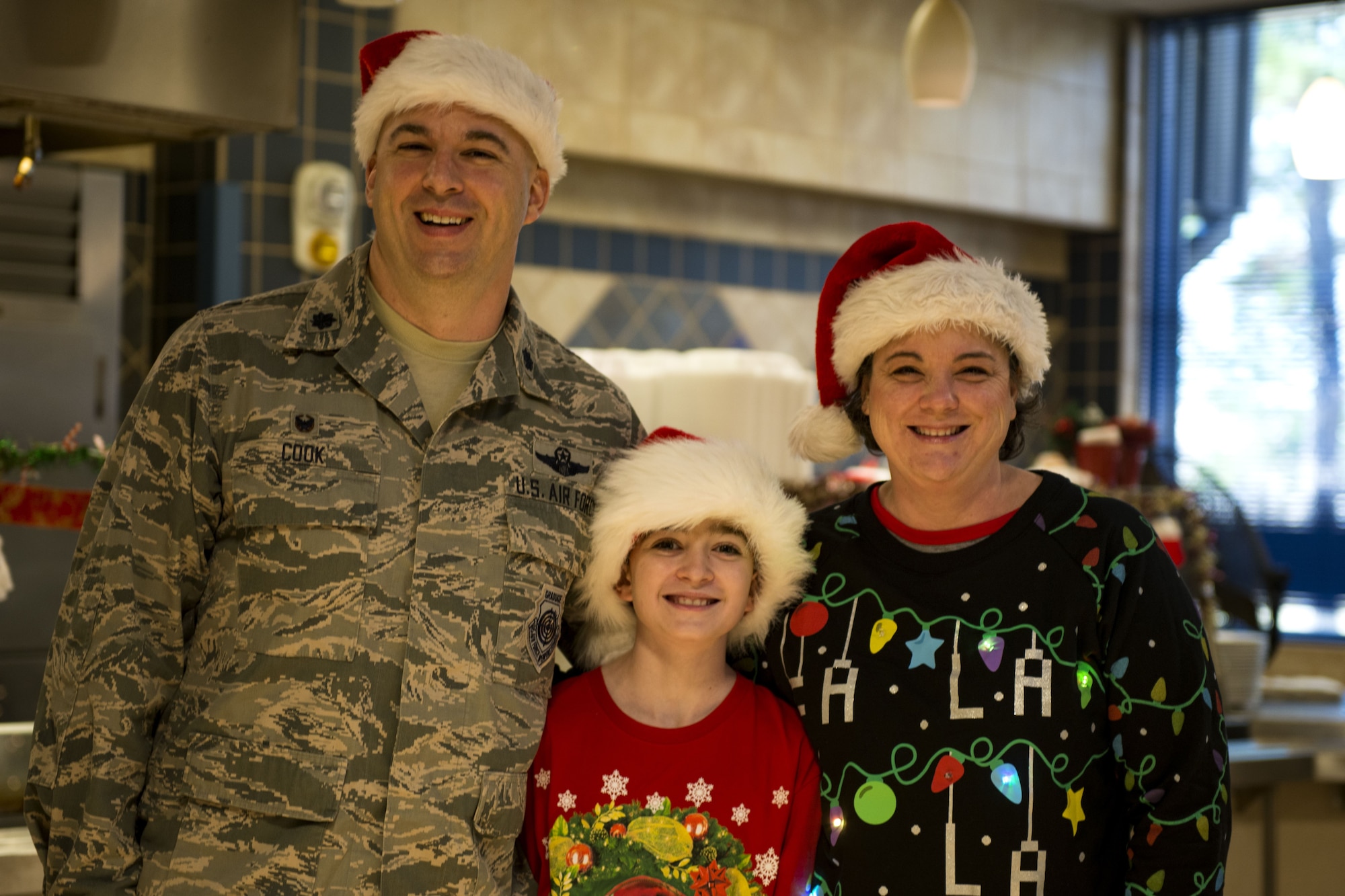 Lt. Col. Gerald Cook, left, 76th Fighter Squadron commander, his son, Justin, middle, and his wife, Catherine, right, pose for a photo on Christmas Day in the Georgia Pines Dining Facility, Dec. 25, 2017, at Moody Air Force Base, Ga. The Christmas meal was an opportunity for Airmen, retirees, dependents and leadership to enjoy a traditional Christmas meal. (U.S. Air Force photo by Airman 1st Class Erick Requadt)