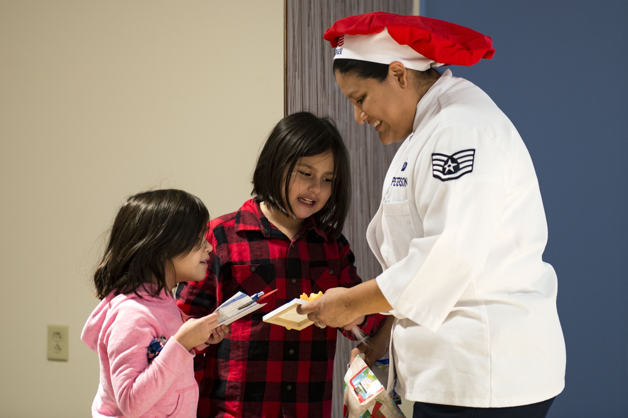 Staff Sgt. Anna Peterson, 23d Force Support Squadron dining facility manager, opens a gift from her daughters on Christmas Day in the Georgia Pines Dining Facility, Dec. 25, 2017, at Moody Air Force Base, Ga. The Christmas meal was an opportunity for Airmen, retirees, dependents and leadership to enjoy a traditional Christmas meal. (U.S. Air Force photo by Airman 1st Class Erick Requadt)