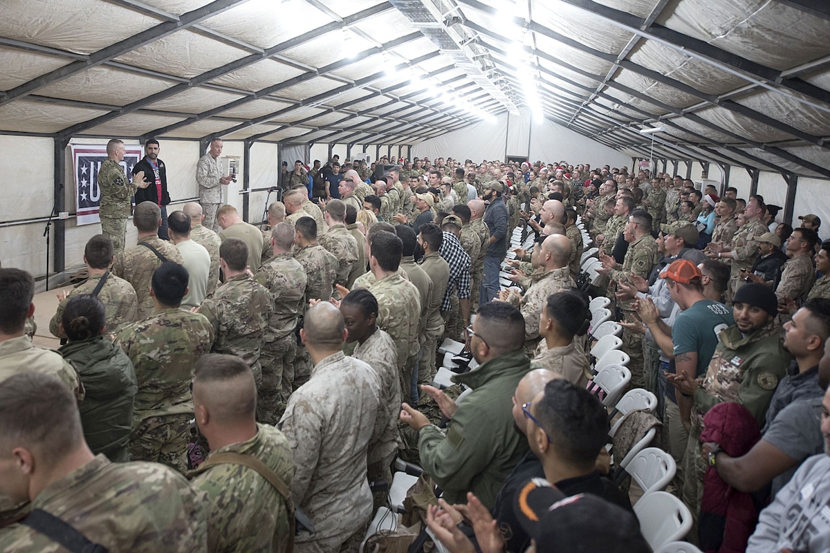 The chairman of the Joint Chiefs of Staff stands on stage and speaks to service members.