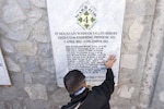 A Medal of Honor recipient kneels at a memorial.