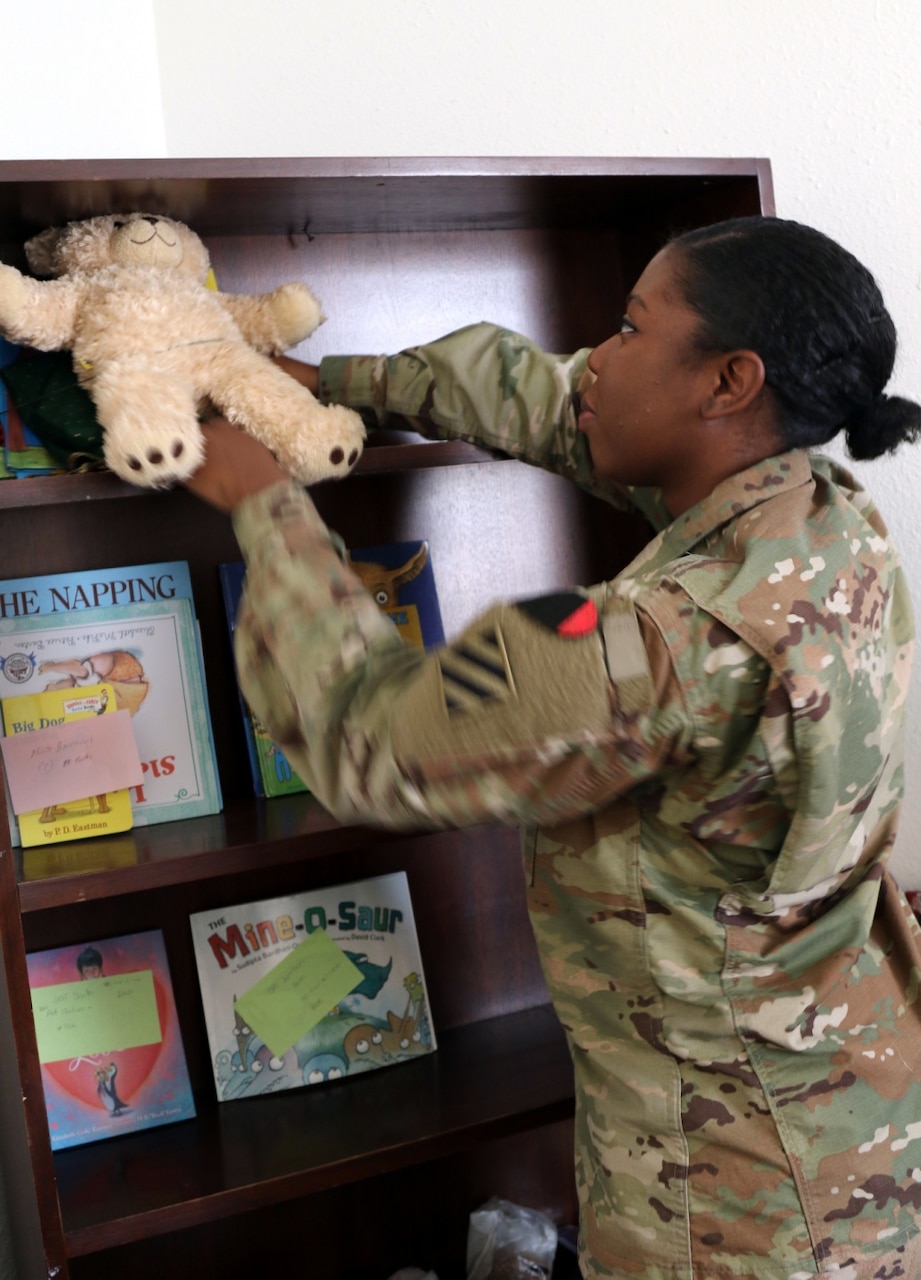 Army Pfc. Hertaycious King, a religious affairs specialist with Special Troops Battalion, 3rd Infantry Division Resolute Support Sustainment Brigade, puts away books and toys at Bagram Airfield, Afghanistan.