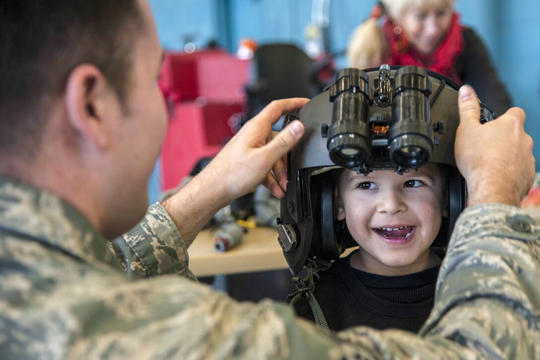 An airman adjusts a helmet being worn by a child.