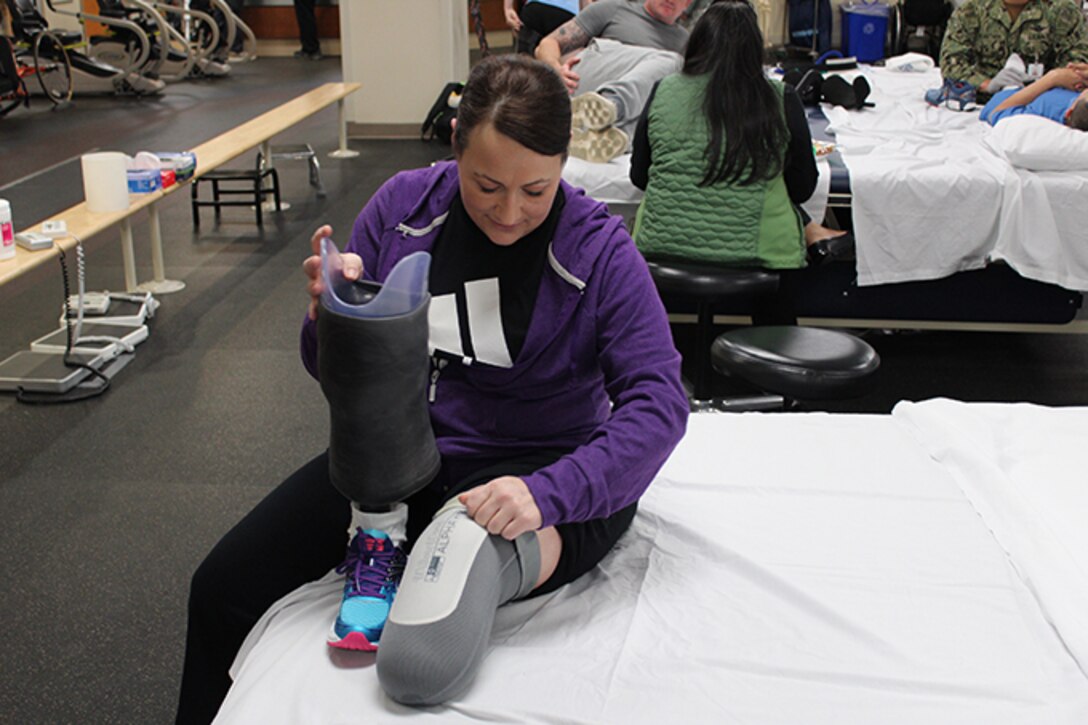 Maj. Stephanie Proellochs carefully inspects her leg and prosthesis after a round of physical therapy exercises at Walter Reed National Military Medical Center, Nov. 15, 2017. Proellochs underwent an amputation as a result of a malignant tumor that spread. (U.S. Air Force photo by Karina Luis)