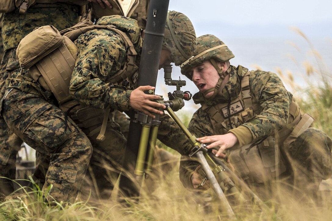 Two Marines adjust a mortar system.