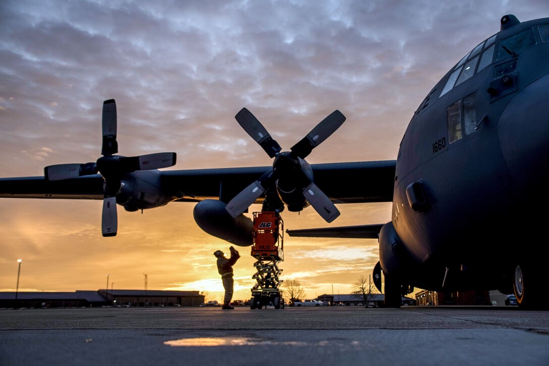 Airmen work near the wing and propeller of an aircraft.