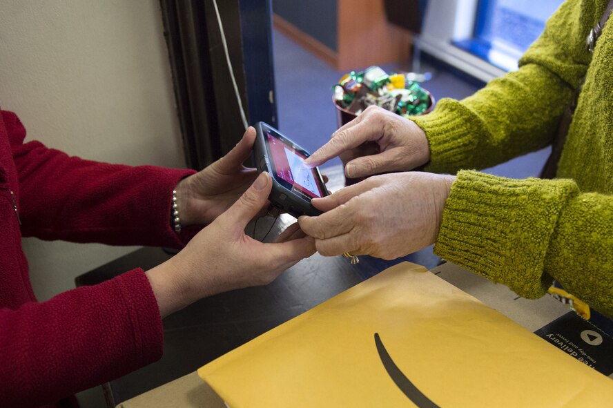 A base resident signs for her package at the post office at RAF Alconbury, Dec. 19, 2017. The signing is a base wide system for package accountability. (U.S. Air Force photo by Airman 1st Class Chase Sousa)