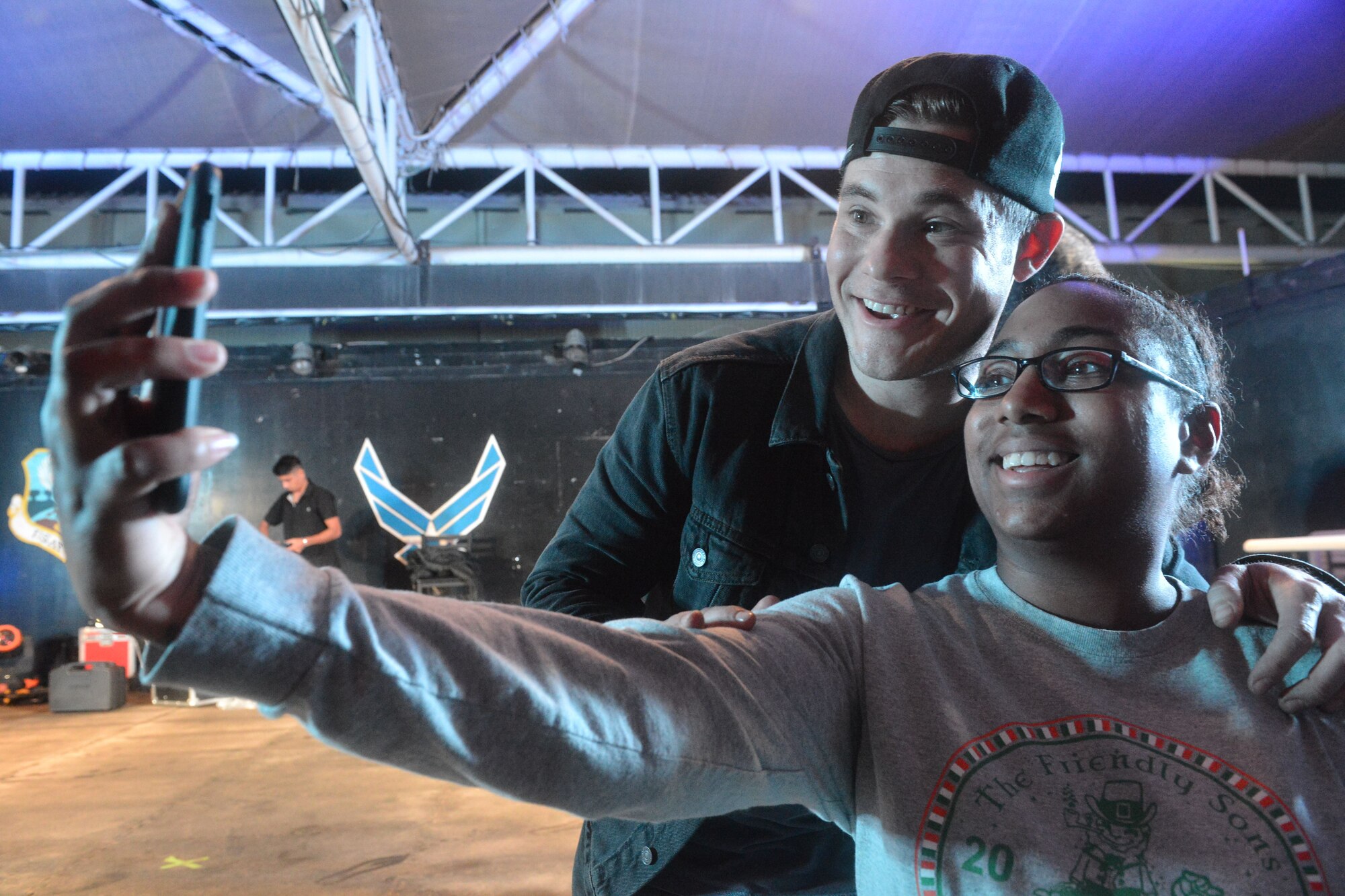 Actor Adam Devine takes a selfie with Airman 1st Class Tyana Holly, 380th Expeditionary Communications Squadron, Client Systems Technician, during the 2017 Chairman's USO Holiday Tour at Al Dhafra Air Base, Unite Arab Emirates, Dec. 22, 2017.
 U.S. Marine Corps Gen. Joe Dunford, Chairman of the Joint Chiefs of Staff, hosts this tour to spread holiday cheer to service members deployed and stationed overseas. 

 (U.S. Air Force photo by Tech. Sgt. Anthony Nelson Jr.)