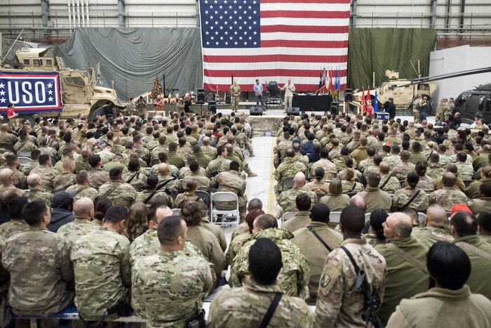 Chairman of the joint chiefs of staff speaks to service members from a stage.