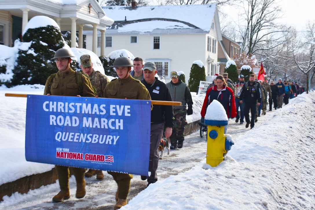 Soldiers and service member families march on a snowy sidewalk.