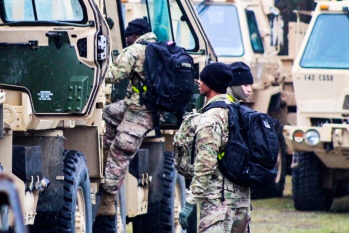 Soldiers climb into vehicles.