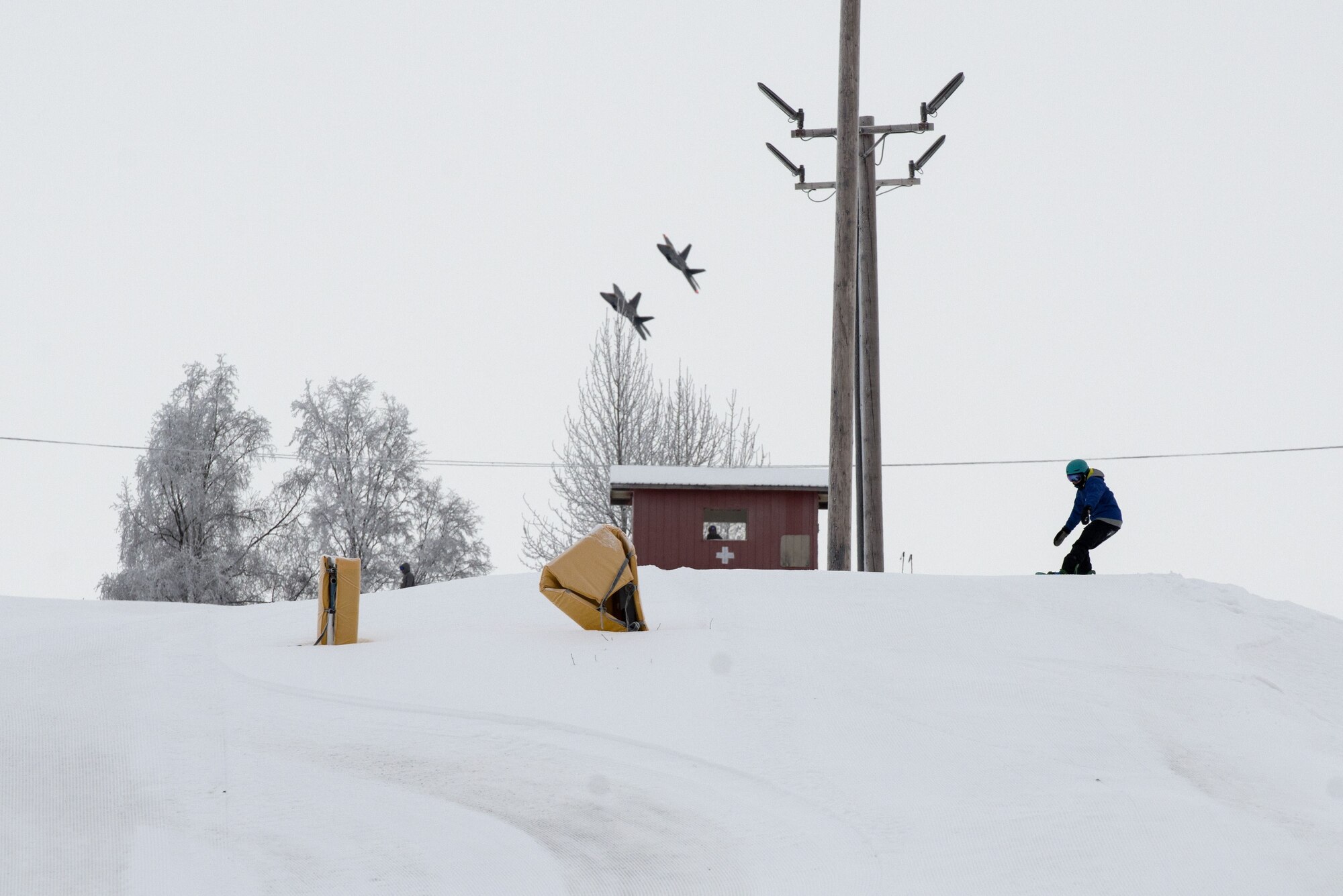 A snowboarder prepares to go down Hillberg Ski Area with F-22 Raptors in the background during Winterfest at Joint Base Elmendorf-Richardson, Alaska, Dec. 21, 2017. Winterfest was a winter solstice celebration hosted by Hillberg for anyone with base access and offered a plethora of events from noon to as late at 8 p.m.