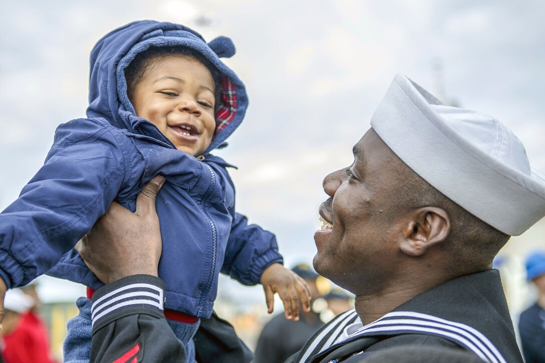 A sailor holds up a young child