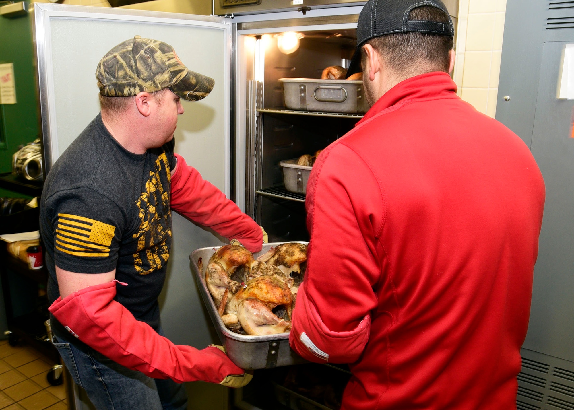 Members of the Montana Air National Guard carry a pan of cooked turkeys to a warming oven at the 120th Airlift Wing Dining Facility at the Great Falls International Airport in Great Falls, Montana Dec. 24, 2017. The guard personnel volunteered to prepare 50 turkeys, dressing and gravy and delivered the food to the Great Falls Senior Citizen Center to be served during the 25th Annual Danny Berg Memorial Christmas Dinner. (U.S. Air National Guard photo/Senior Master Sgt. Eric Peterson)