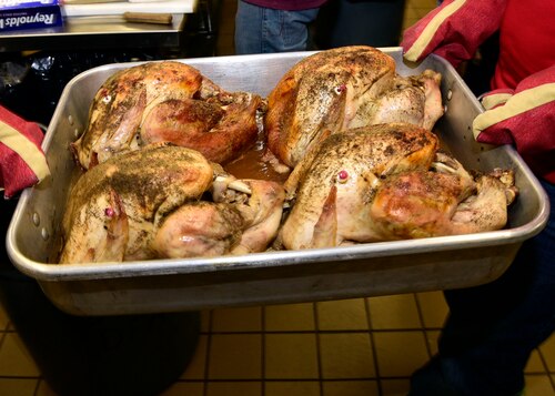 Freshly cooked turkeys are carried to members of the Montana Air National Guard to carve. The guard personnel volunteered to prepare 50 turkeys, dressing and gravy and then delivered the food to the Great Falls Senior Citizen Center to be served during the 25th Annual Danny Berg Memorial Christmas Dinner. (U.S. Air National Guard photo/Senior Master Sgt. Eric Peterson)