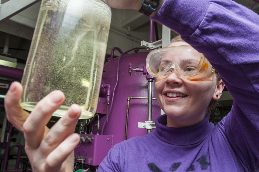 A sailor holds a clear container with fuel.