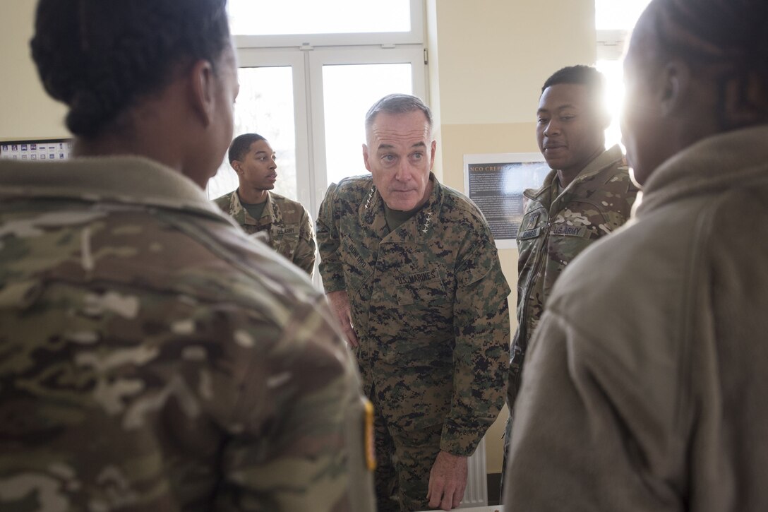 The chairman of the Joint Chiefs of Staff leans forward to speak to service members.