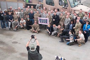 A group of people holding a USO sign pose for a photograph.