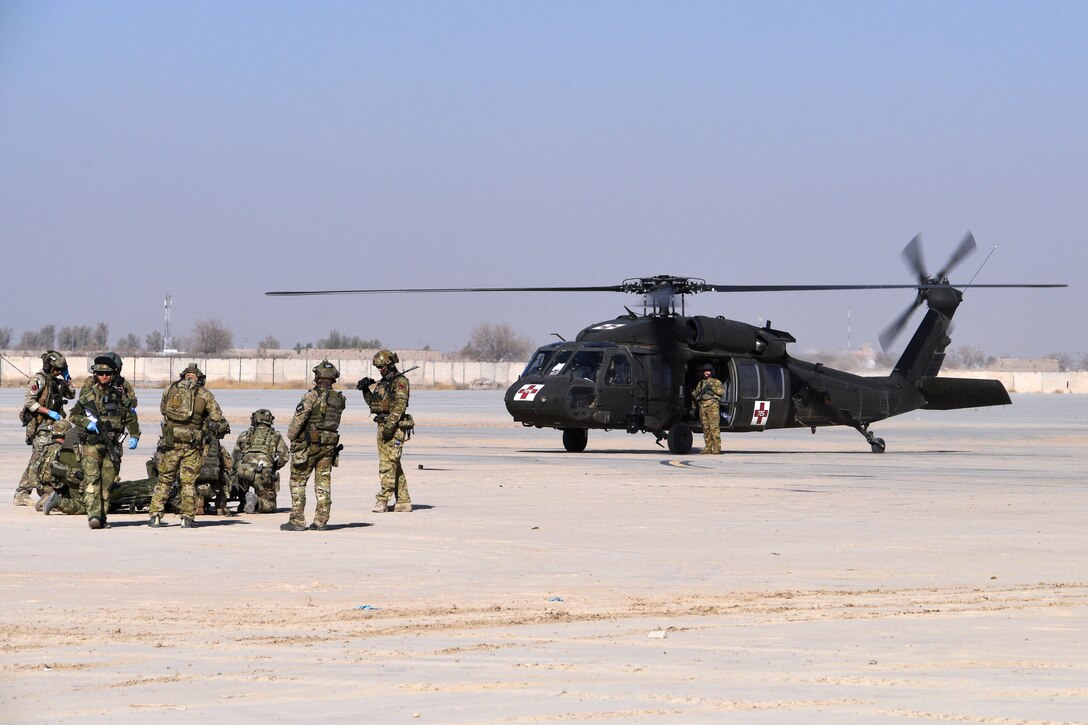 A group of U.S. and Polish service members stand near a helicopter.