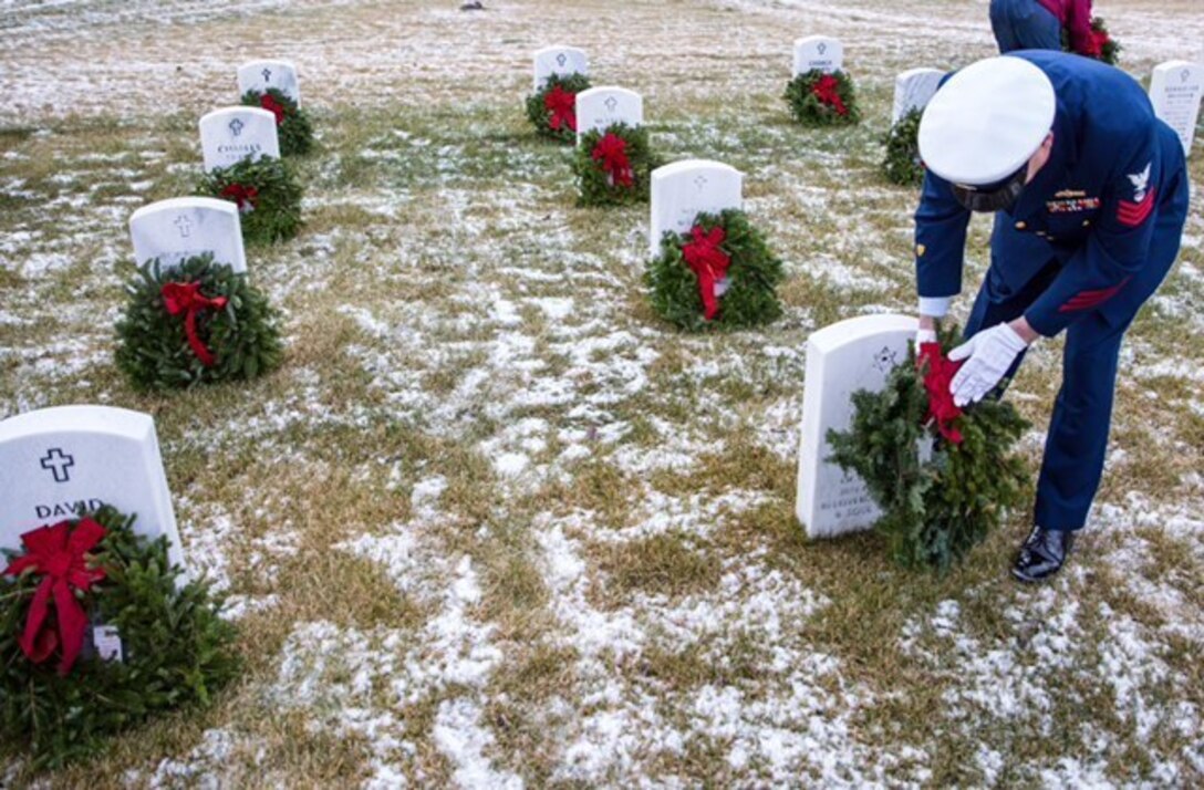 Image of Coast Guard Sector Anchorage crewmember placing a wreath on a veteran's grave.