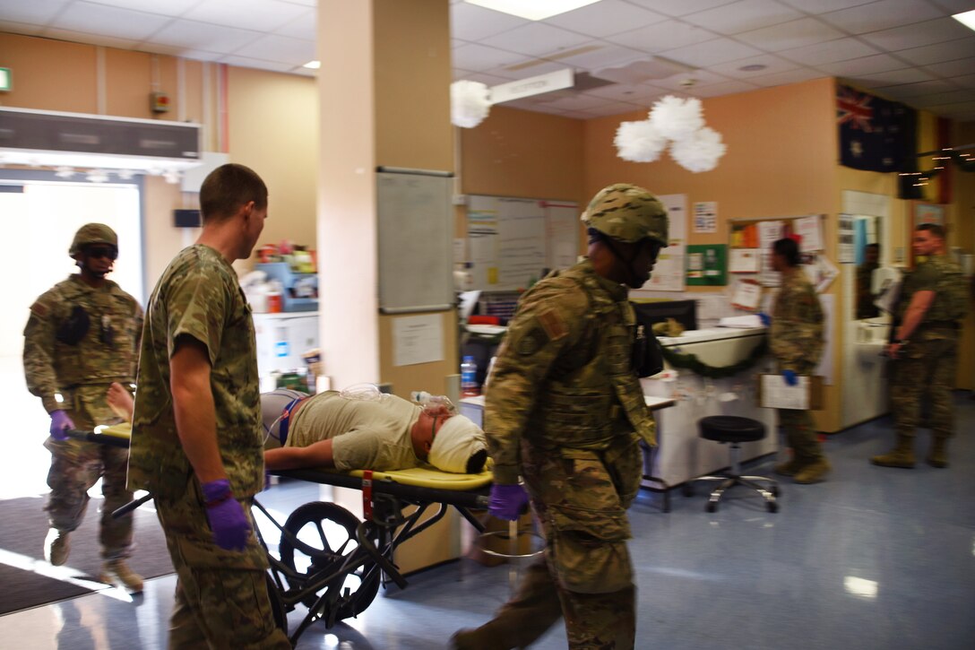 U.S. service members wheel a person through a room.