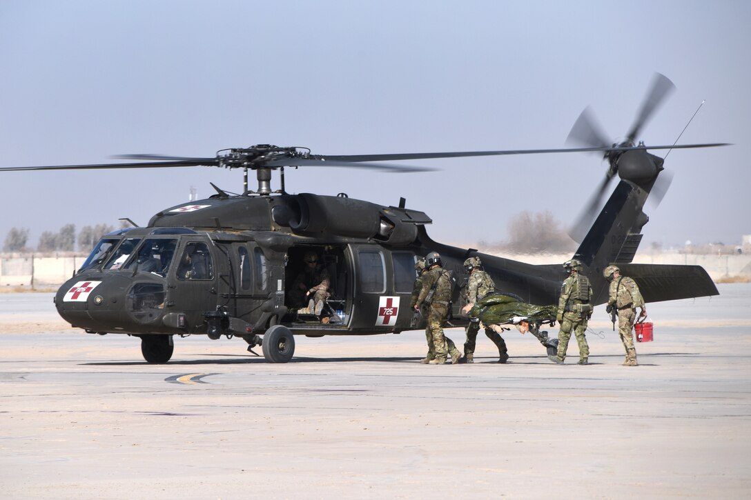 U.S. and Polish service members carry a person on a stretcher to a helicopter.