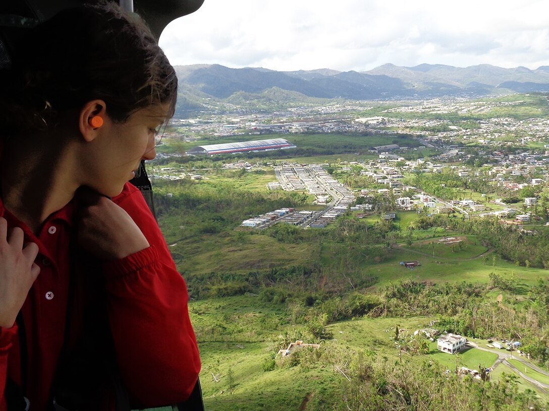 woman looks out helicopter window at Puerto rico after hurricane maria