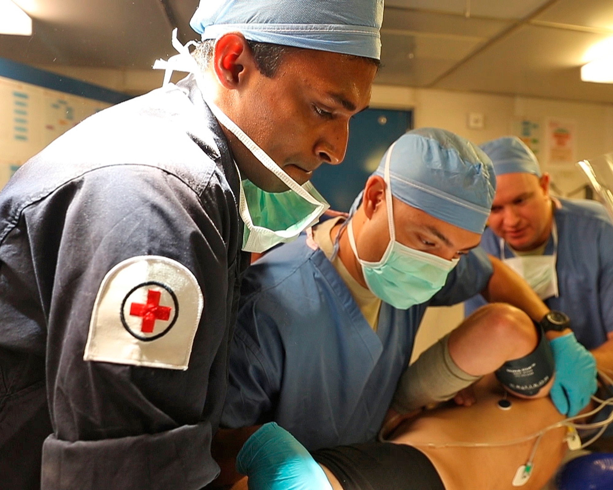 From left, LMT Shavi Locu-Enderage RN, U.S. Air Force Capt. Carlo Lobato, an anesthesiologist with the 379th Expeditionary Medical Operations Squadron, and U.S. Air Force Capt. Omar Carrasco, an operating room nurse with the 379th EMDOS, conduct a full body survey of a Royal Marine with simulated injuries onboard the HMS Ocean, Jan. 26, 2017. Members of the Royal Navy and 379th EMDOS came together during coalition exercise Azraq Serpent to simulate receiving casualties in a maritime environment. (Courtesy photo, Royal Navy)