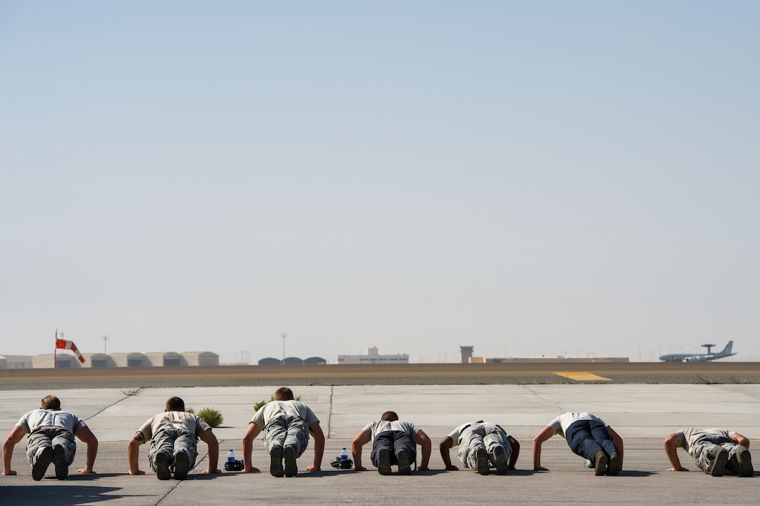 380th Expeditionary Aircraft Maintenance Squadron Airmen complete pushups while an E-3 Sentry departs and completes a sortie in support of Combined Joint Task Force-Operation Inherent Resolve at an undisclosed location in Southwest Asia, Feb. 2, 2017. The E-3 Sentry maintainers complete as many push-ups as possible while the aircraft takes off. Since November 2016, no E-3 Sentry has missed a scheduled sortie due to maintenance issues. (U.S. Air Force photo by Senior Airman Tyler Woodward)