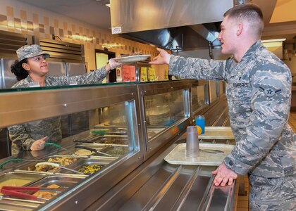 Airman 1st Class Ashley Gonzalez, 628th Force Support Squadron food service apprentice, serves a plate of beef stir fry to an Airman at the Robert D. Gaylor Dining Facility here, Jan. 31, 2017. The dining facility will closed for repairs March 1. Airmen on meal cards will receive a basic allowance for subsistence during the 10-month project.