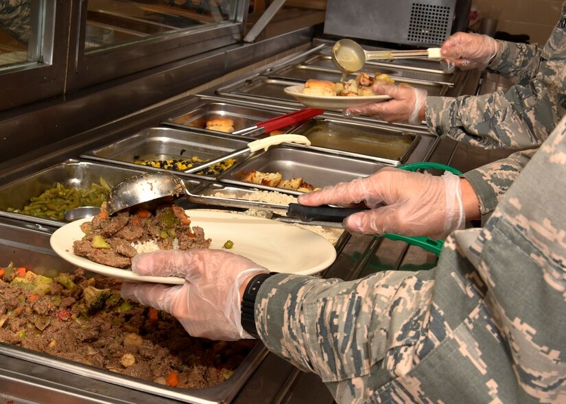 Airman 1st Class Jonathan Cruz, 628th Force Support Squadron food service apprentice, scoops beef stir fry onto a plate at the Robert D. Gaylor Dining Facility here, Jan. 31, 2017. The dining facility will close for repairs March 1. Airmen on meal cards will receive a basic allowance for subsistence during the 10-month project.