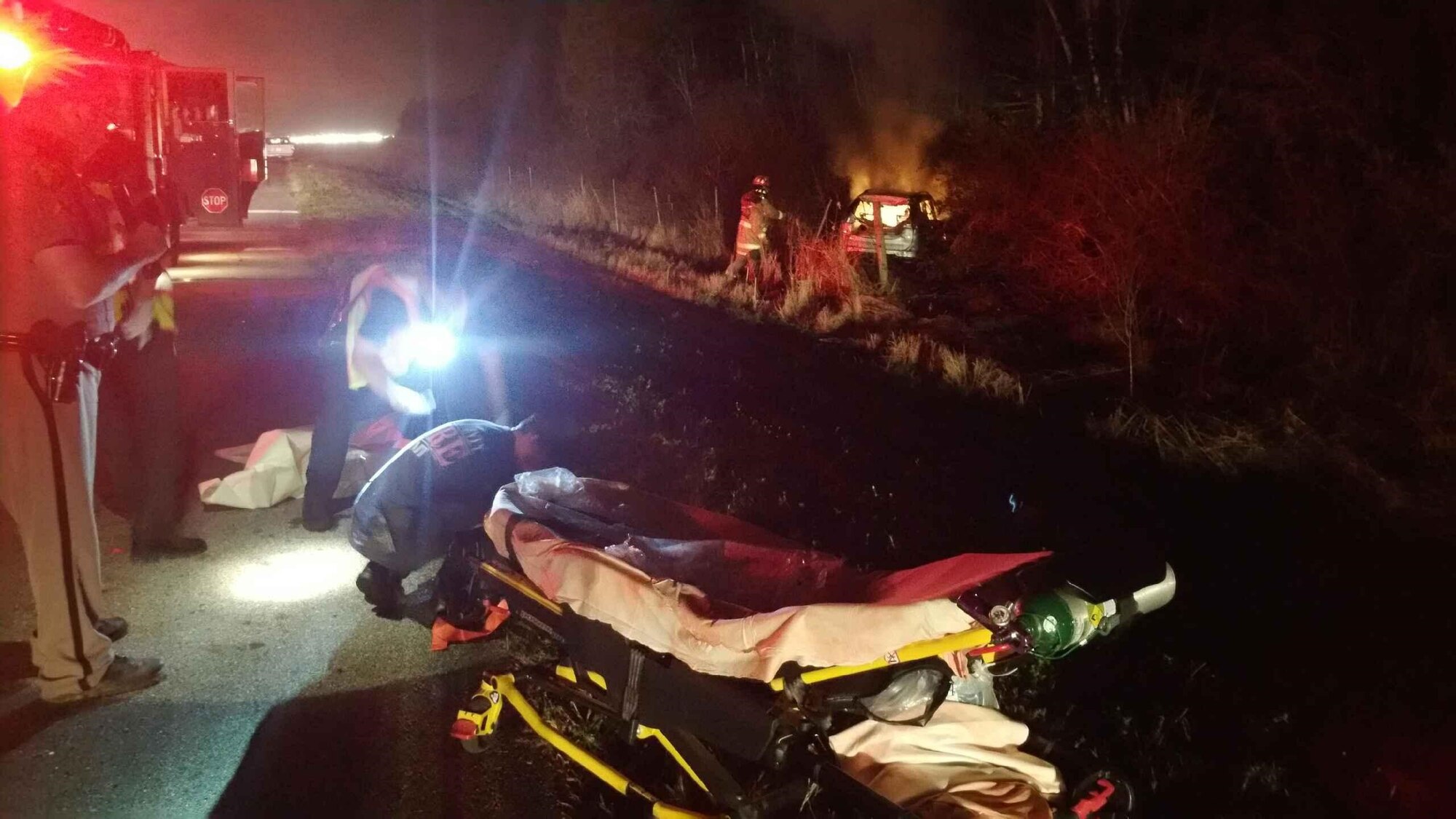 A firefighter extinguishes a car fire shortly after Airman 1st Class PeeJay Jack pulled the unconscious driver from the vehicle and away to safety. Jack witnessed the car drive off the road and catch fire, and then selflessly put his own life in harm’s way to pull the man from the inferno. (Courtesy Photo)