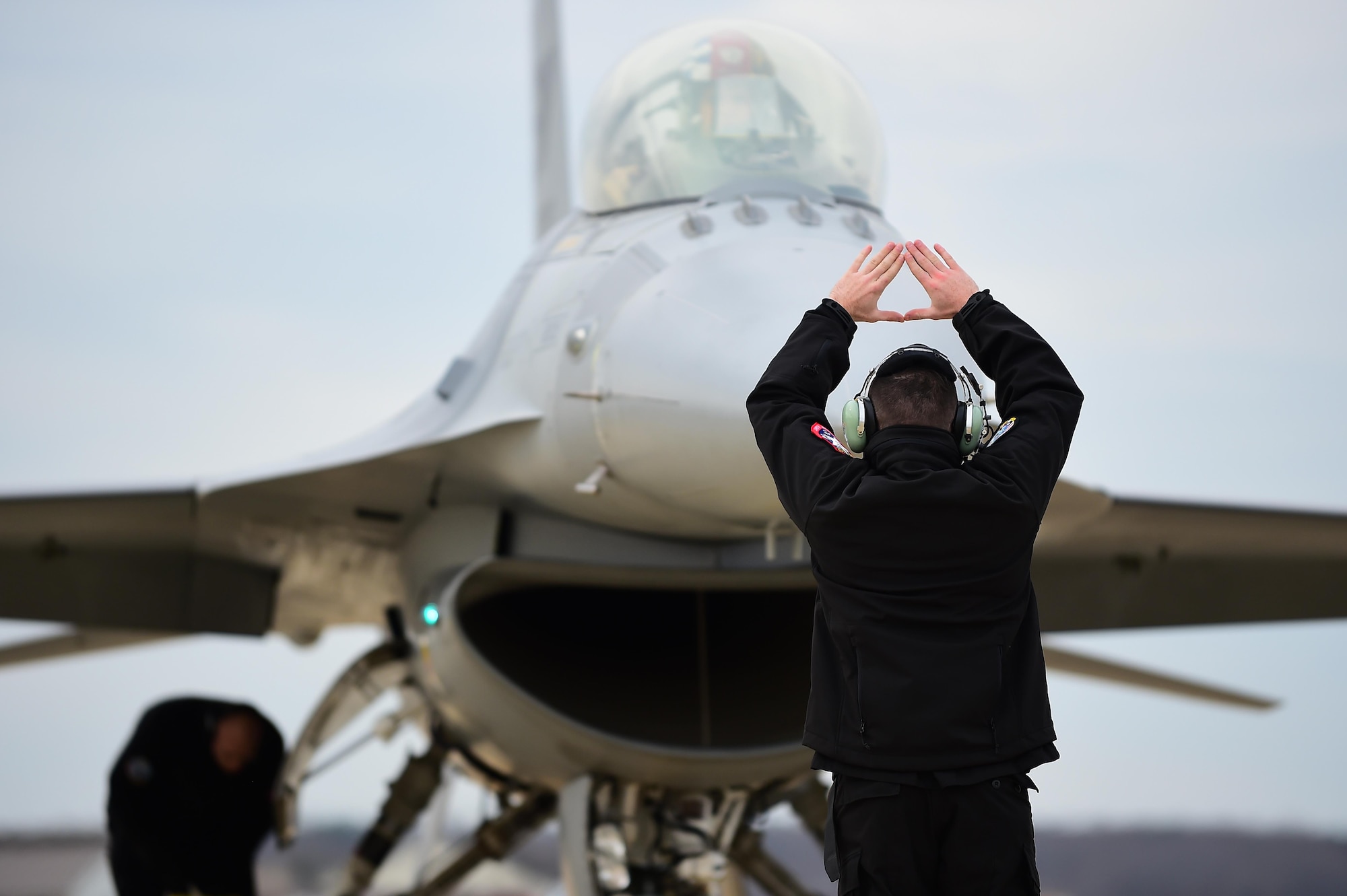 U.S. Air Force Senior Airman Adam Armstrong, F-16 Viper Demonstration Team crew chief, signals to a pilot after landing at Joint Base Langley-Eustis, Va., Jan. 31, 2017. Crew chiefs assigned to the team, travel to each destination with their aircraft, ensuring the aircraft is ready for flight at all times. (U.S. Air Force photo by Senior Airman Kimberly Nagle)