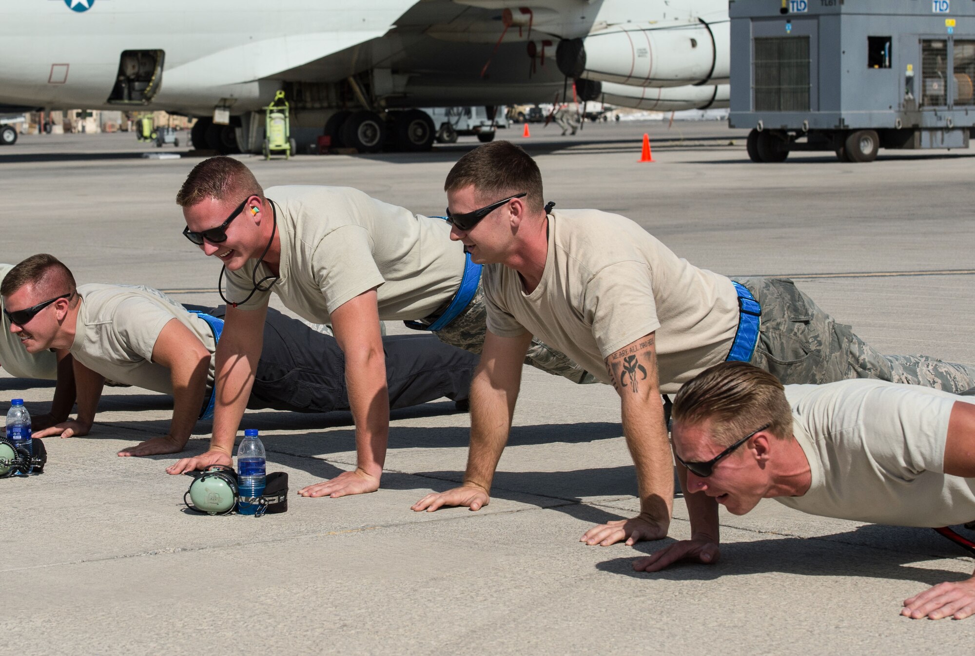 380th Expeditionary Aircraft Maintenance Squadron Airmen laugh while completing pushups during an E-3 Sentry departure at an undisclosed location in Southwest Asia, Feb. 2, 2017. The E-3 Sentry maintainers complete as many push-ups as possible while the aircraft takes off. Since November 2016, no E-3 Sentry has missed a scheduled sortie due to maintenance issues. (U.S. Air Force photo by Senior Airman Tyler Woodward)