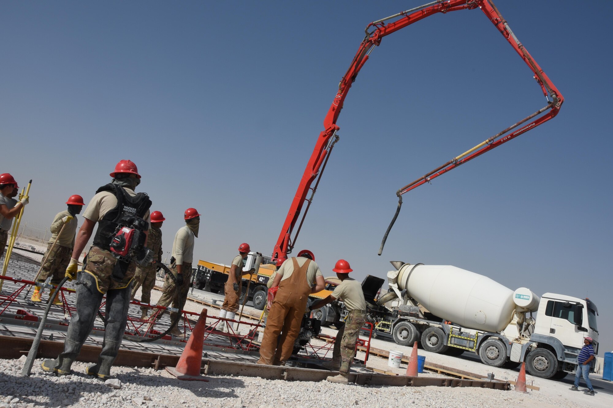 Airmen with the 557th Expeditionary RED HORSE Squadron wait as cement is sucked out of a cement mixer truck into a pump truck at Al Udeid Air Base, Qatar, Jan. 31, 2017. Airmen with 557th ERHS are currently constructing two facilities at the close air support ramp to support administration, operators, and supply functions for all aircraft maintenance units there. (U.S. Air Force photo by Senior Airman Cynthia A. Innocenti)