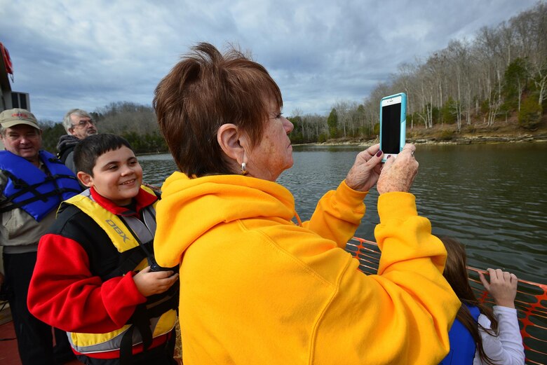 A group of sightseers onboard a U.S. Army Corps of Engineers open barge scan the tree lines with binoculars and cameras for a sighting of eagles at Dale Hollow Lake.  Every year groups flock hundreds of miles for the opportunity to scan the treetops in search of wintering bald eagles at Dale Hollow Lake, which straddles the border of Tennessee and Kentucky.  