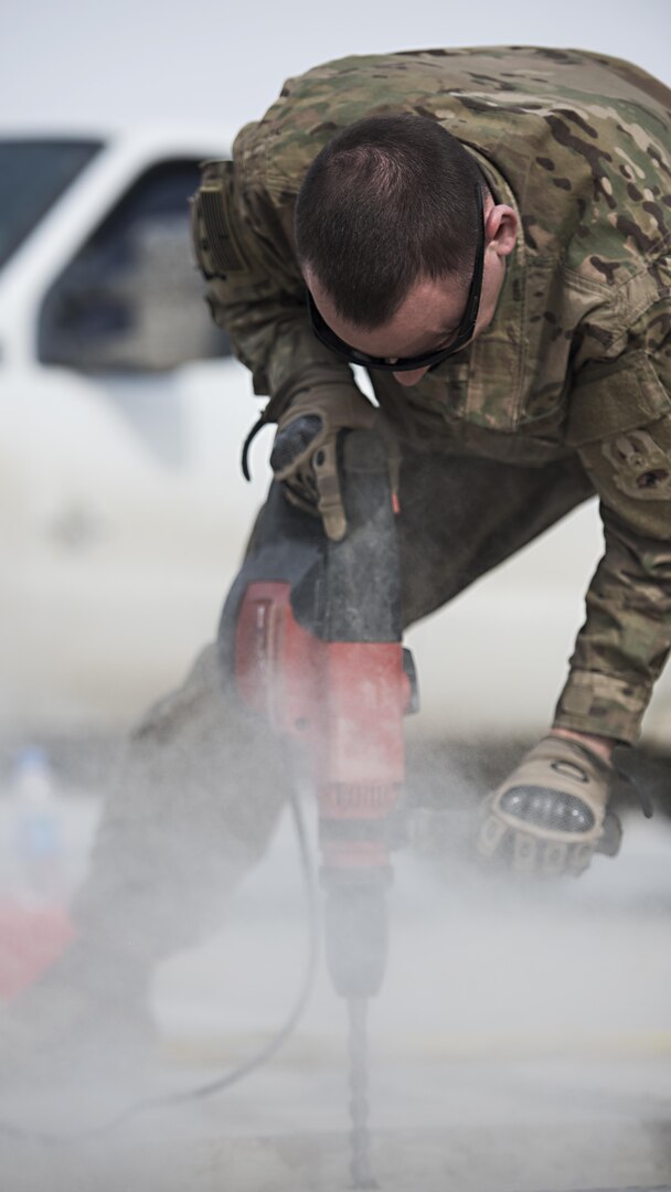 Senior Airman Adam Parizo, 455th Expeditionary Civil Engineer Squadron Power Productions specialist, drills into concrete Feb. 1, 2017 at Bagram Airfield, Afghanistan. The 455th ECES Pavements and Construction; Power Productions; and Structures Shops teamed up to repair a strip of damaged runway. (U.S. Air Force photo by Staff Sgt. Katherine Spessa)