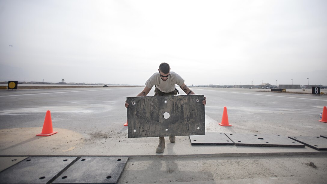 Airman 1st Class Abram Burkhart, 455th Expeditionary Civil Engineer Squadron structures specialist, lays a pad on the runway Feb. 1, 2017 at Bagram Airfield, Afghanistan. Members of the 455th ECES replaced a strip of the runway with polyethylene pads to mitigate wear and tear from aircraft traffic. (U.S. Air Force photo by Staff Sgt. Katherine Spessa)