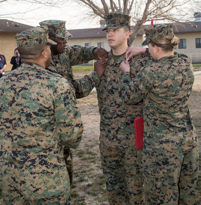 Cpl. Luis Gomez, a military policeman assigned to the MCLB Barstow Command Inspector General's Office, is pinned by MSgt. Donald Lumpkins, command inspector chief, and Sgt Monica Hilpisch, stableman with the Marine Corps Mounted Color Guard, upon being meritoriously promoted to sergeant, Feb 2. This is the Long Beach, Calif. native's secon meritorious promotion in the last 18 months.