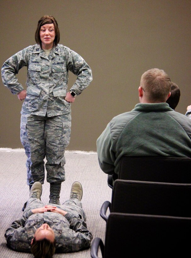 Smiling and energized for the day, Capt. Laura Raineri, a nurse in the 932nd Aeromedical Staging Squadron (ASTS), discusses first aid and training plans, along with the best way forward regarding taking care of the simulated patient, on the ground, at her feet.  She taught a class on patient transportation and managing resources safely for the January Unit Training Assembly at Scott Air Force Base, Ill. More training is ahead with the February UTA this weekend on Saturday and Sunday.  The ASTS is a squadron under the 932nd Medical Group near Belleville, Ill. (U.S. Air Force photo by Lt. Col. Stan Paregien)
