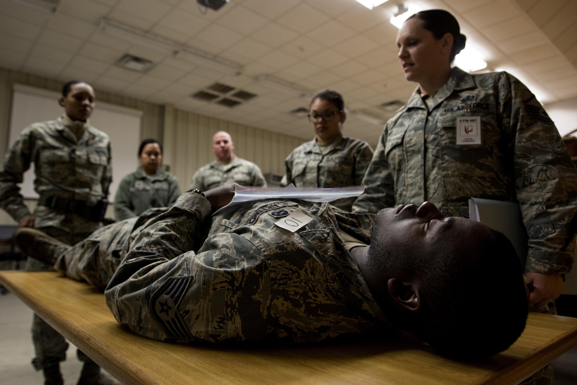Staff Sgt. Damyan Jackson, 4th Logistic Readiness Squadron vehicle operator, acts as a casualty during exercise Coronet Warrior 17-01, Jan. 31, 2017, at Seymour Johnson Air Force Base, North Carolina. Master Sgt. Julie Nix, 4th Force Support Squadron wing inspection team member, evaluated the mortuary affairs procedures of participating 4th FSS Airmen. (U.S. Air Force photo by Airman Shawna L. Keyes)