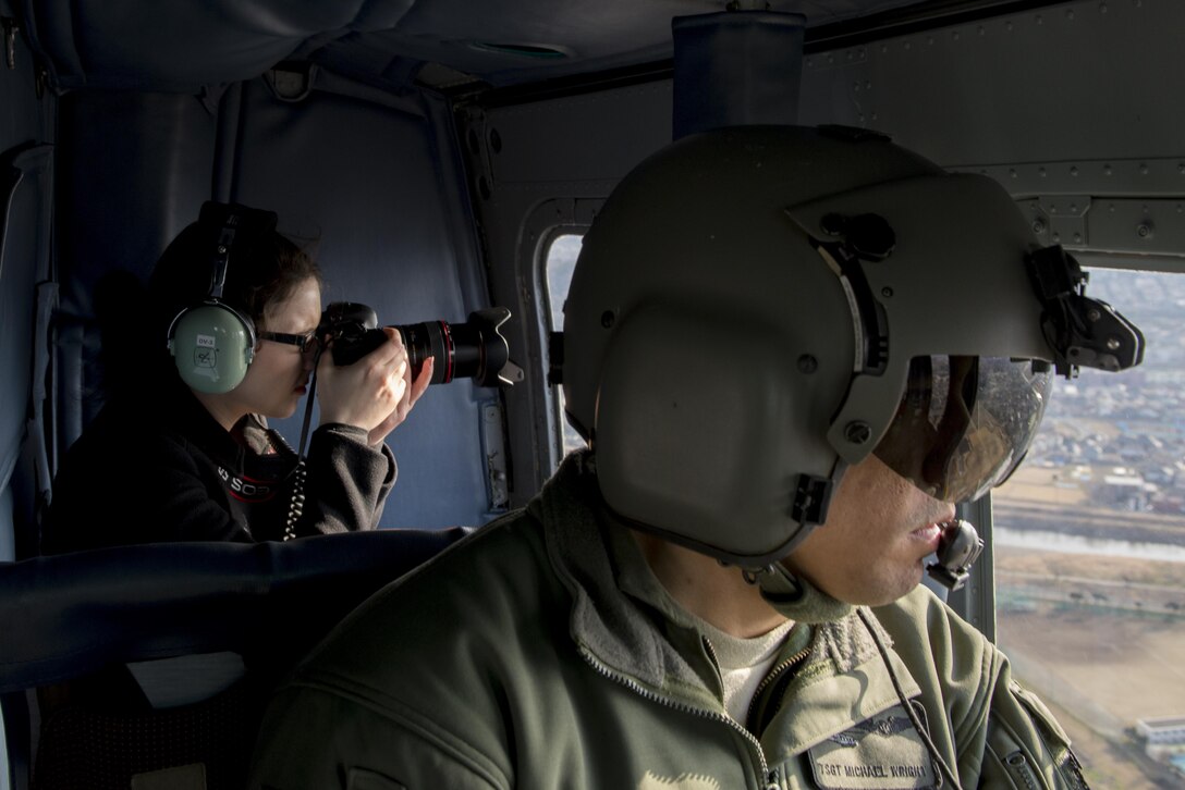 Tech. Sgt. Michael Wright, 459th Airlift Squadron special mission aviator evaluator, looks out a window of a UH-1N Iroquois as a participant in a Spouse Orientation Flight takes photos Feb. 1, 2017, near Yokota Air Base, Japan. Participants who flew in a UH-1N were given an aerial tour of down town Tokyo. (U.S. Air Force photo by Airman 1st Class Donald Hudson)