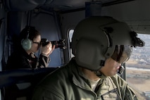 Tech. Sgt. Michael Wright, 459th Airlift Squadron special mission aviator evaluator, looks out a window of a UH-1N Iroquois as a participant in a Spouse Orientation Flight takes photos Feb. 1, 2017, near Yokota Air Base, Japan. Participants who flew in a UH-1N were given an aerial tour of down town Tokyo. (U.S. Air Force photo by Airman 1st Class Donald Hudson)