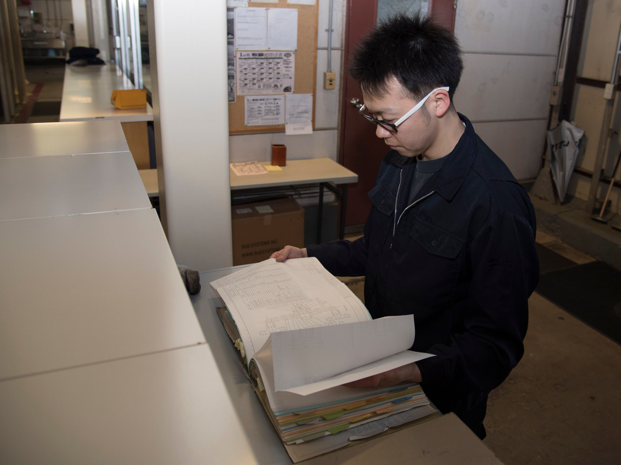 Shingo Matsumura, a 35th Civil Engineer Squadron boiler operator, looks through a steam plant maintenance book at Misawa Air Base, Japan, Jan. 30, 2017. The maintenance book includes blueprints for the boiler rooms and instructions for performing all maintenance checks. Misawa contains 11 different steam plant locations across the base. (U.S. Air Force photo by Airman 1st Class Sadie Colbert)