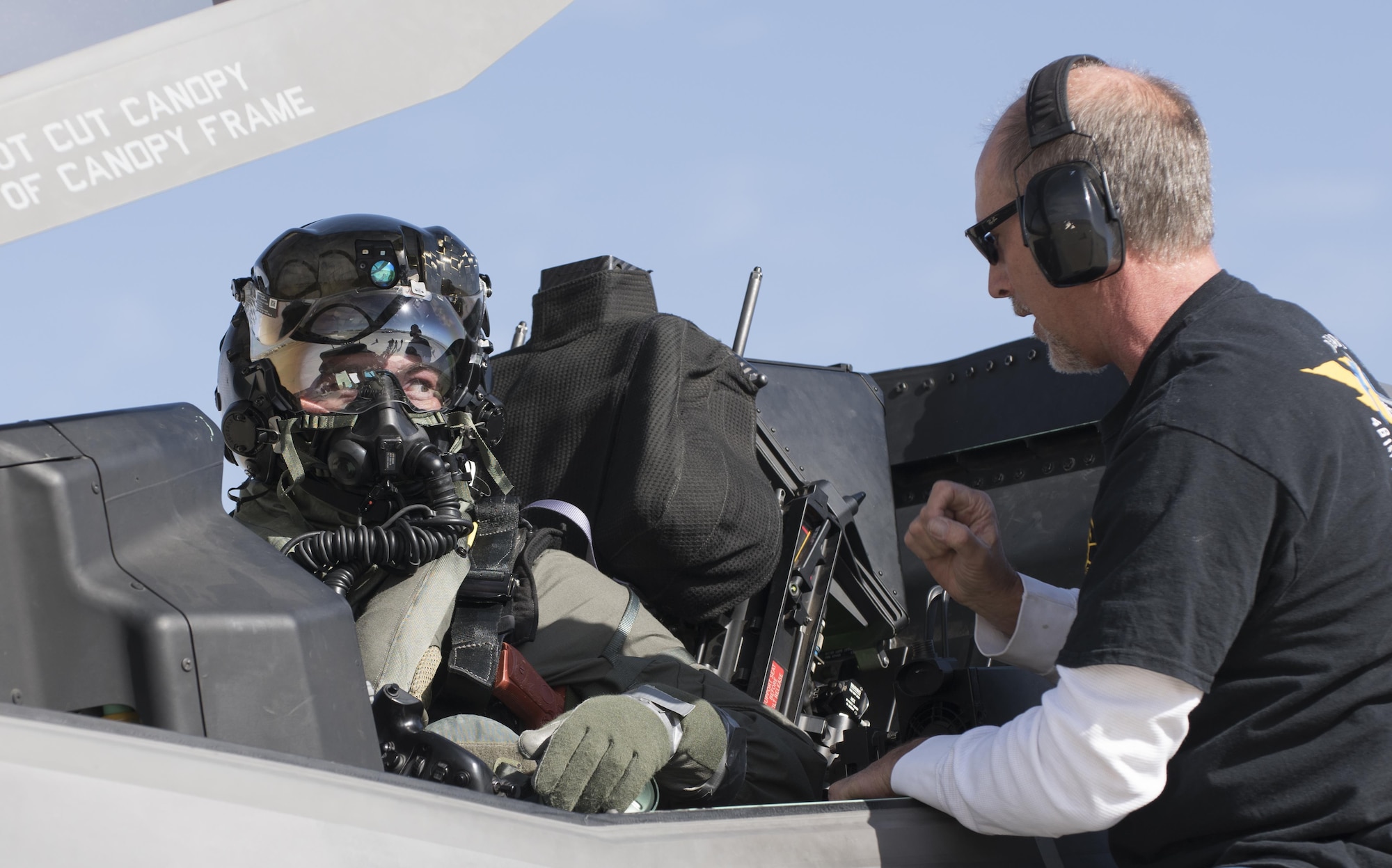 Marine Corps Maj. Aaron Frey, 461st Flight Test Squadron, speaks with Jim Kristo, 461st FLTS, while seated in an F-35B Jan. 6 during tests of a chemical/biological pilot ensemble. (U.S. Air Force photo by Brad White)