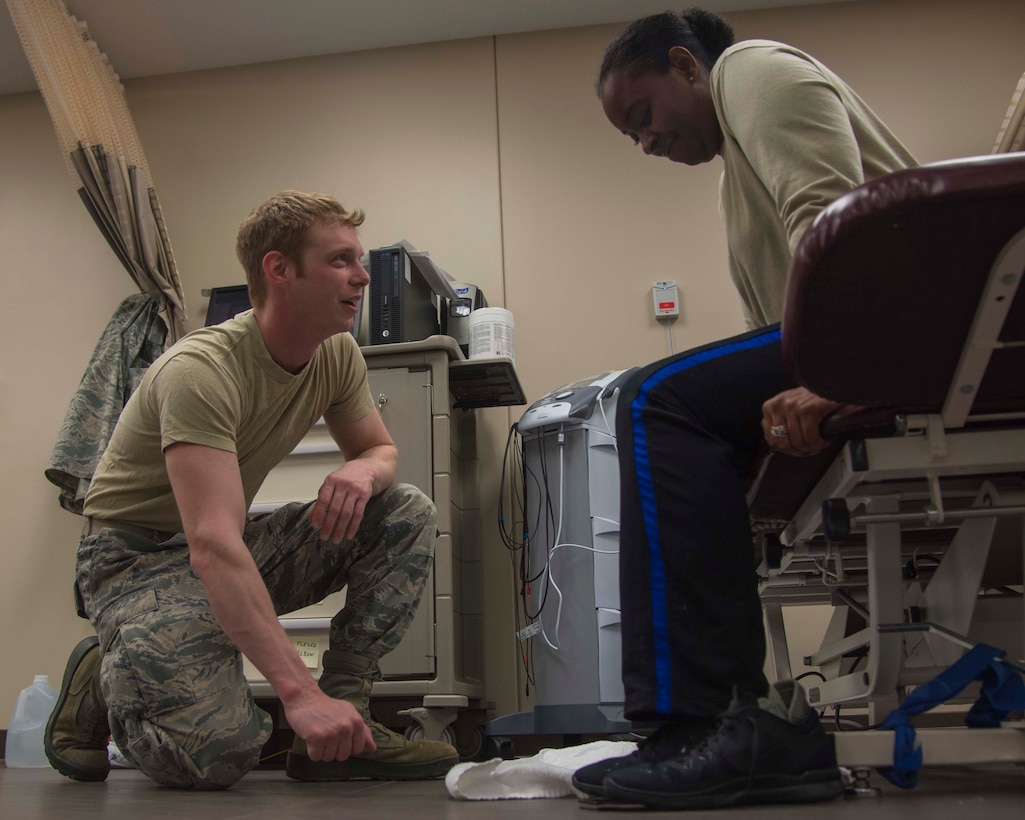 Staff Sgt. Kivynn Pabst, left, 779th Medical Group physical medicine technician, kneels down to identify the exercise location for Master Sgt. Christina Chislom, right, Malcolm Grow Medical Center patient, during a physical therapy session at Joint Base Andrews, Md., Feb. 2, 2017. Approximately 15 people work at the physical medicine clinic, which averages 150 patients a day. (U.S. Air Force photo by Airman 1st Class Valentina Lopez)