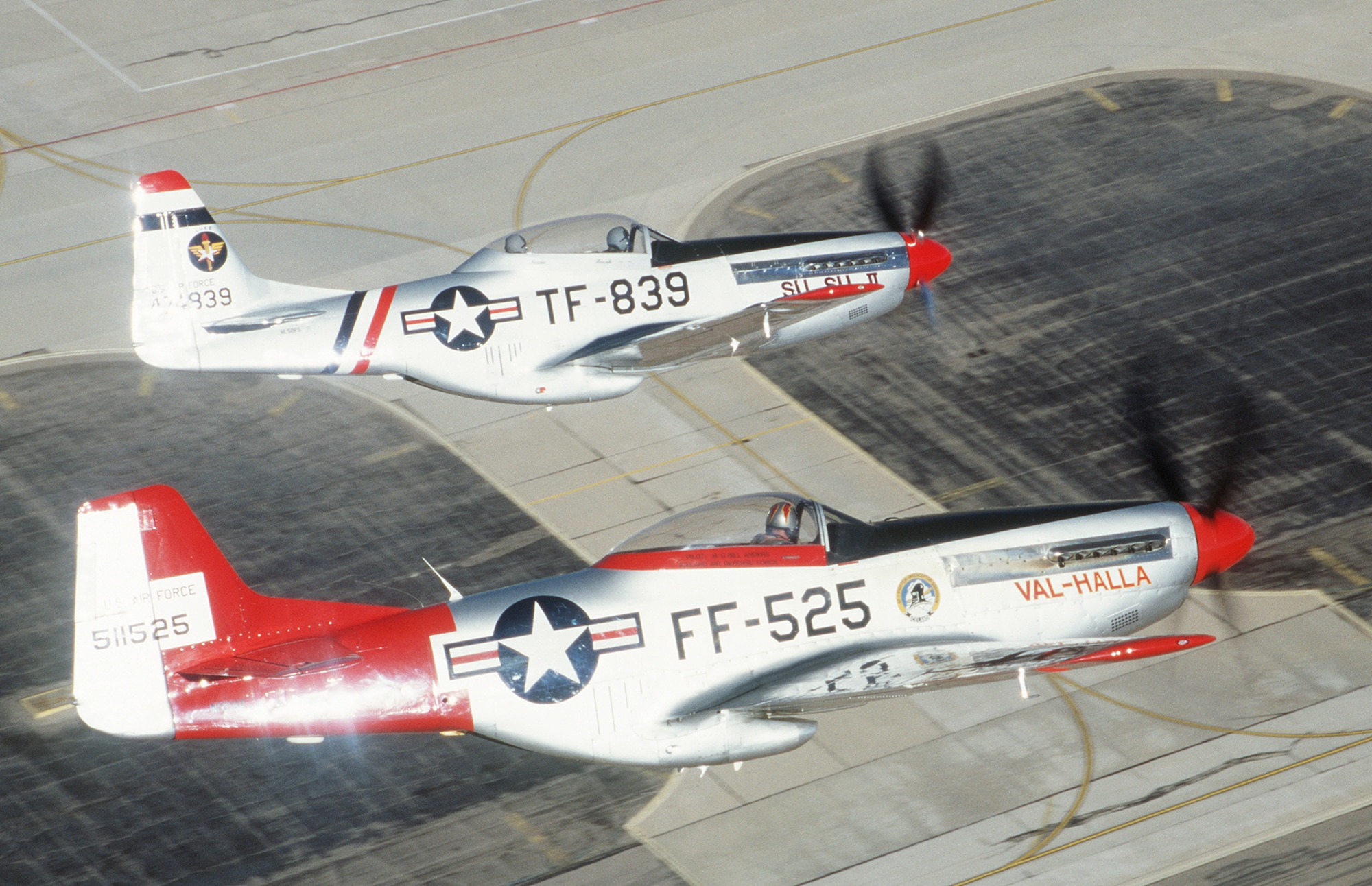 Two P-51 Mustangs shimmer against the parking ramp over Davis-Monthan AFB, AZ while practicing formation flying during a USAF Heritage Conference 2002 training flight. The USAF Heritage conference brings together civilian Heritage pilots and USAF Demonstration Team pilots to discuss safety and practice formation flying in a non-airshow environment.  The USAF heritage aircraft and modern day fighters routinely team together to perform at airshows in the "Heritage Flight" formation but must be certified to fly together before the airshow season begins each year.  USAF  Photo by SSgt. Greg L. Davis.