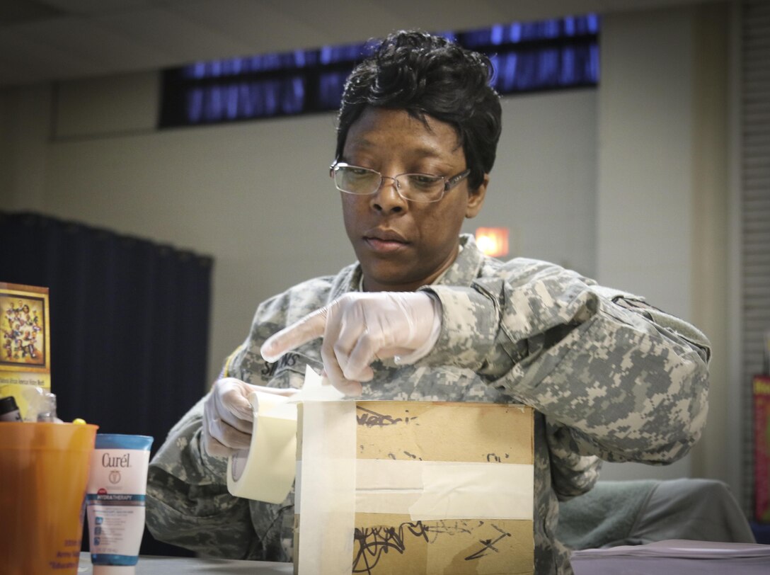 Sgt. 1st Class Lashara Simmons, a human resources noncommissioned officer assigned to the Joint Enabling Capabilities Command, 335th Signal Command (Theater) applies tape to seal a box in order to practice mailing procedures during a Unit Prevention Leader Course being taught at the 335th SC (T) Headquarters in East Point, Georgia Feb. 2.  (Official U.S. Army Reserve photo by Sgt. 1st Class Brent C. Powell)