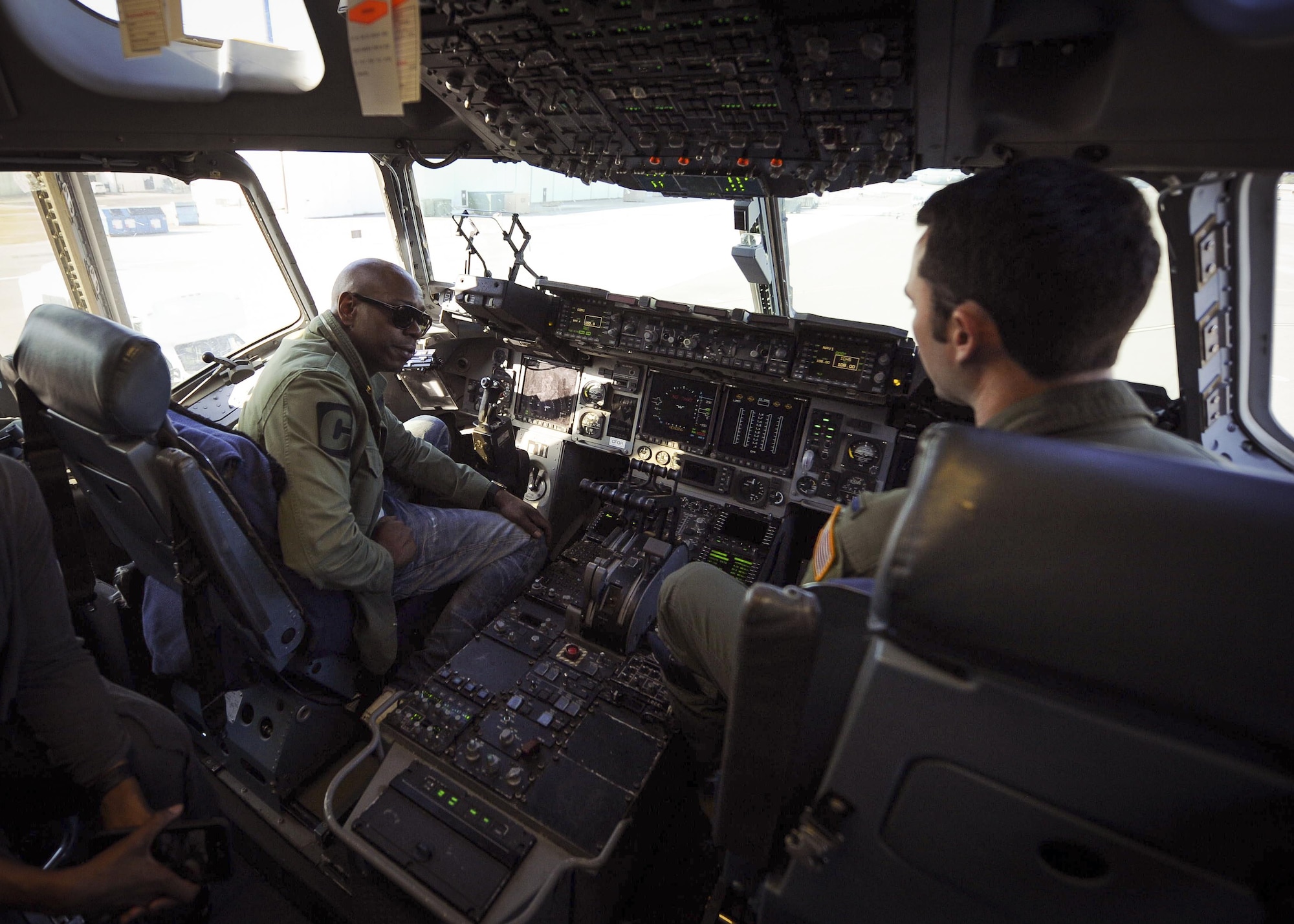 Actor/comedian Dave Chappelle chats with a 315th Airlift Wing pilot on the flight deck of a C-17 Globemaster III static display at Joint Base Charleston, S.C.  Chappelle was in town for his stand-up comedy show when he made the visit to see service members and federal civilians at the base Feb. 2. (U.S. Air Force photo by Senior Airman Tom Brading)