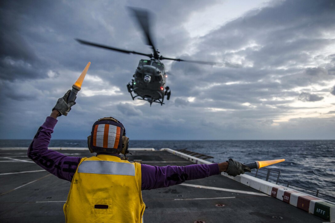 Navy Petty Officer 2nd Class Torien Collins signals to a UH-Y Huey helicopter as it prepares to land on the USS Green Bay in the East China Sea, Feb. 2, 2017. Collins is an aviation boatswain's mate (fuels). The amphibious transport dock ship is patrolling in the Indo-Asia-Pacific region to enhance partnerships and be a ready-response force for any type of contingency. Navy photo by Petty Officer 1st Class Chris Williamson